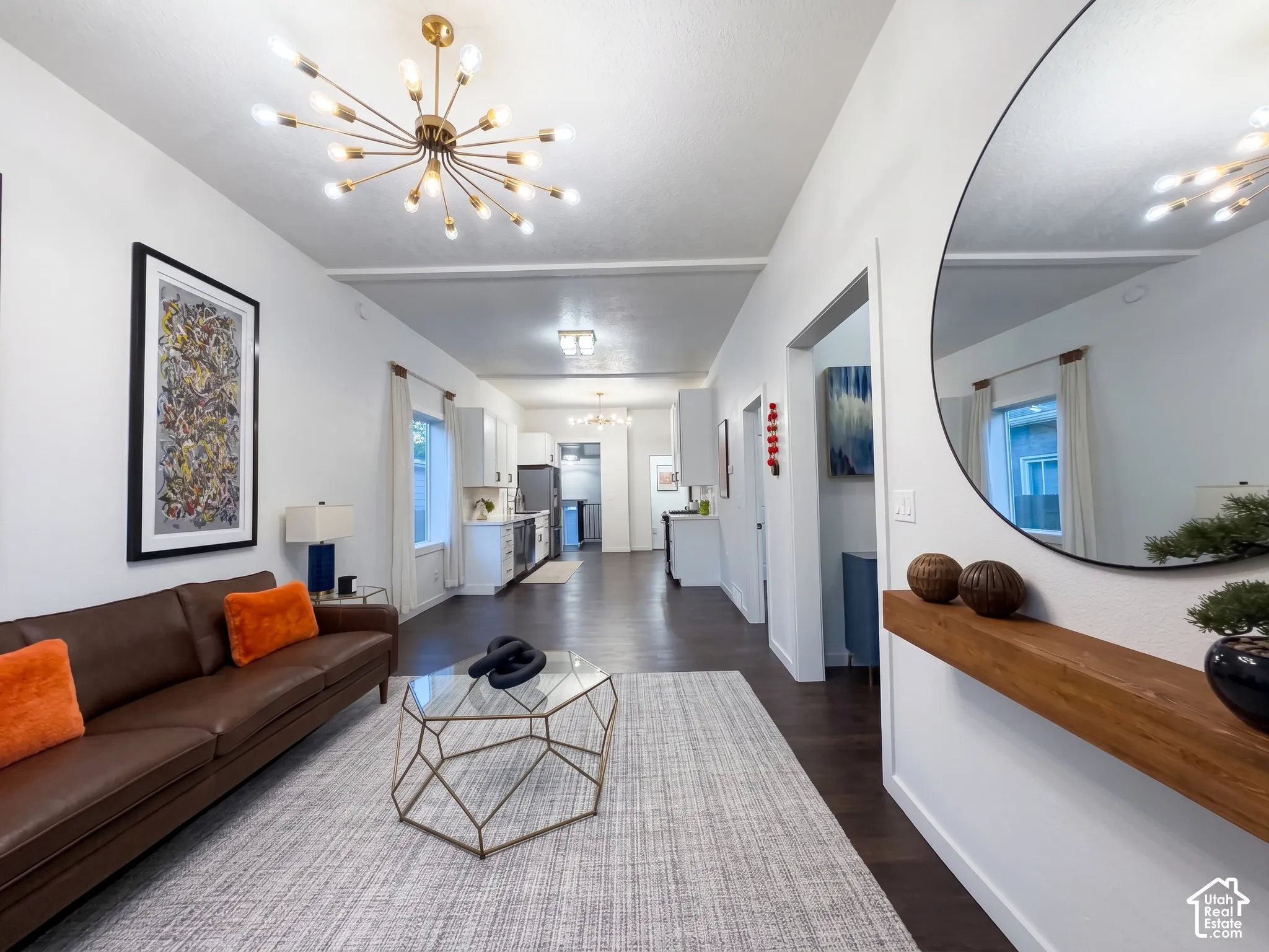 Open-concept living space fully refinished with hardwood flooring, floating shelf, and a contemporary sputnik chandelier and light fixtures.