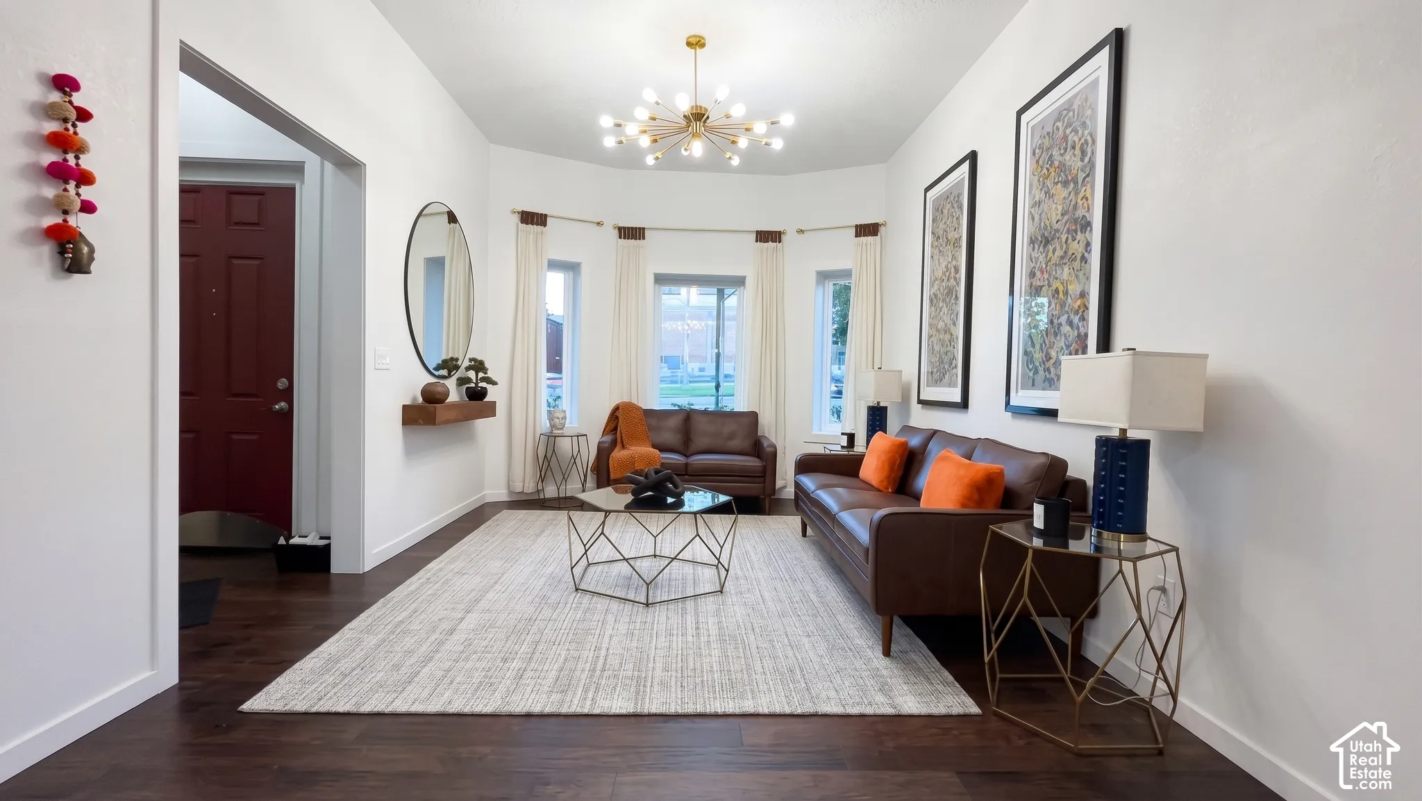 Dark wood-finish flooring, recessed bay window, contemporary chandelier, crisp white walls, and a recessed entryway