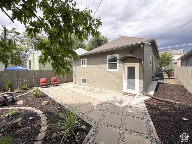 Landscaped yard with stone pavers and gravel pathway, privacy fence, and a covered entryway.