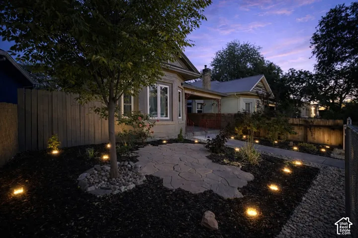 Stone patio with integrated landscape lighting, a mature tree, and surrounding bark mulch offers beauty and low-maintenance.