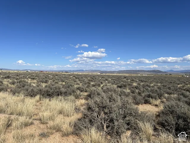 Expansive open terrain with natural vegetation, featuring distant structures and a mountainous horizon