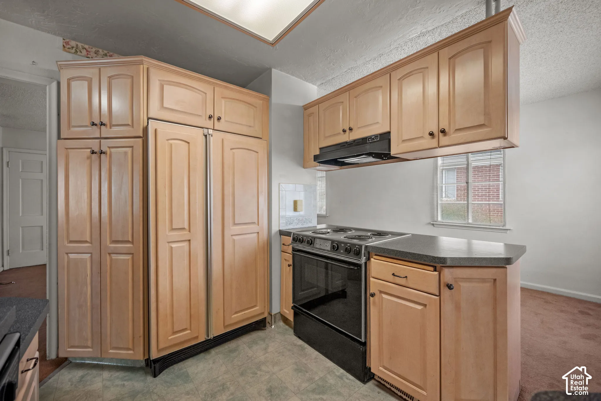Kitchen with wood-finish cabinetry, black appliances, and neutral countertops