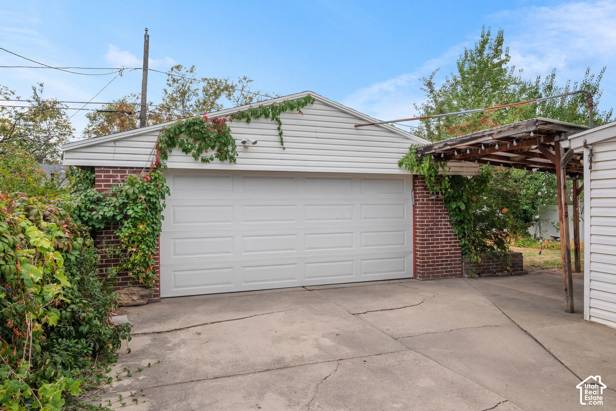 Detached garage with brick and siding exterior, concrete driveway, and covered walkway