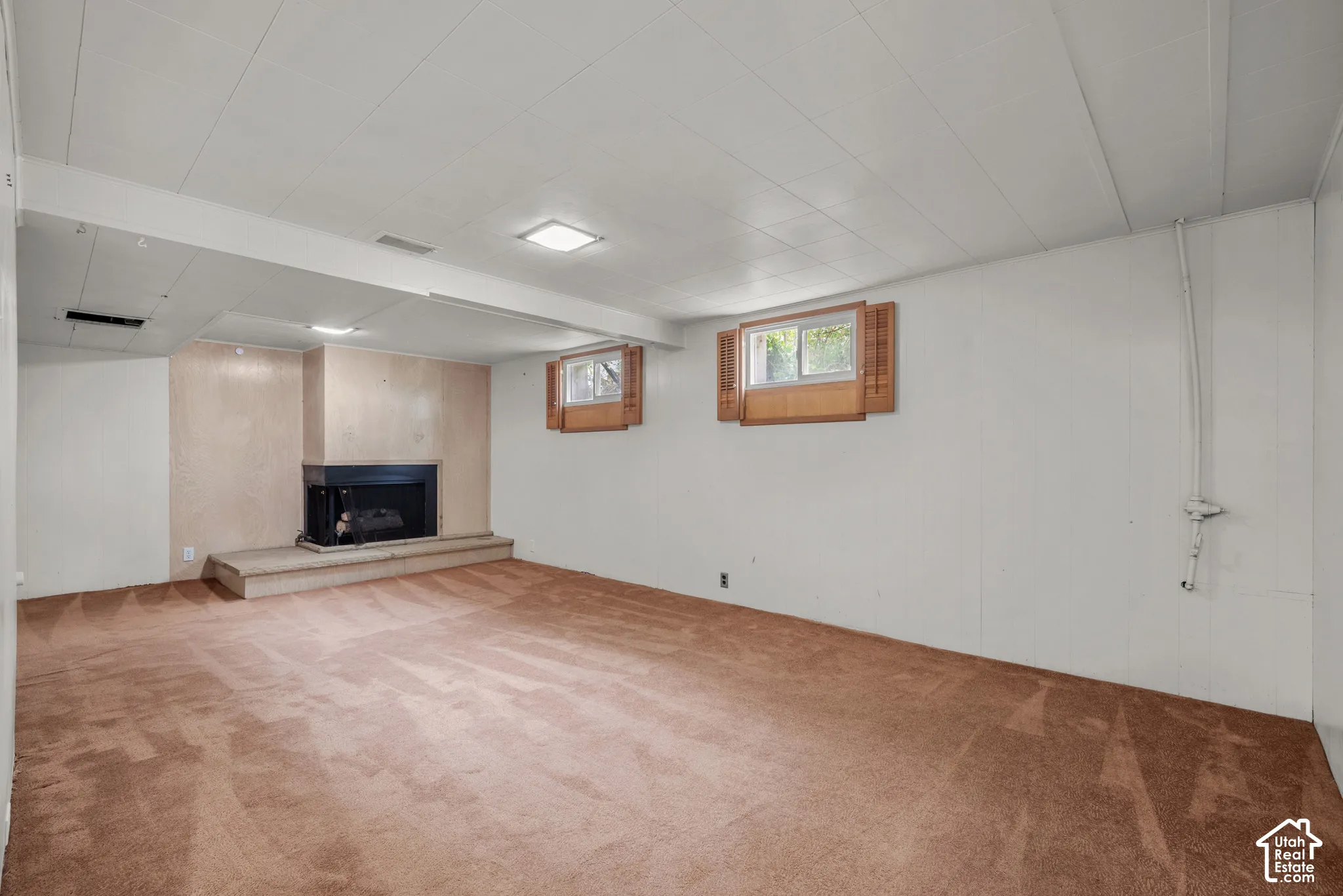 Wood-paneled fireplace with a raised hearth, carpeted flooring, and recessed lighting