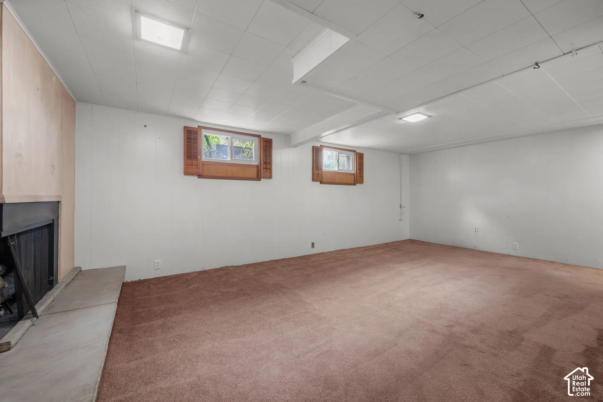 Expansive carpeted area with two windows, a fireplace, and overhead lighting