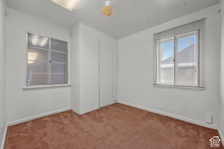 Neutral wall color, wall-to-wall carpeting, and two windows