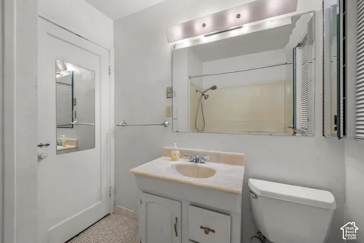 Vanity with a single basin, wall-mounted light fixture, and large mirror