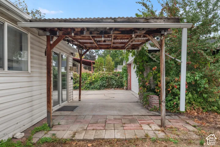 Covered patio featuring a corrugated roof, wood support beams, and a concrete slab
