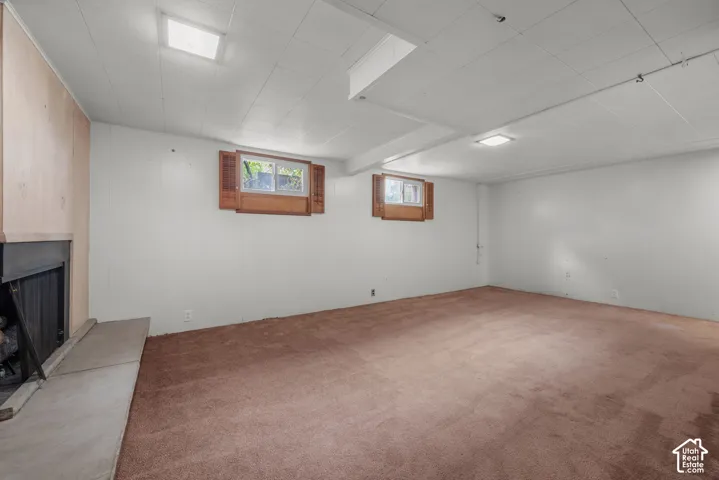Expansive carpeted area with two windows, a fireplace, and overhead lighting