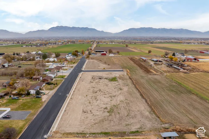 Expansive undeveloped land parcels with paved road access, surrounded by agricultural fields and distant mountains