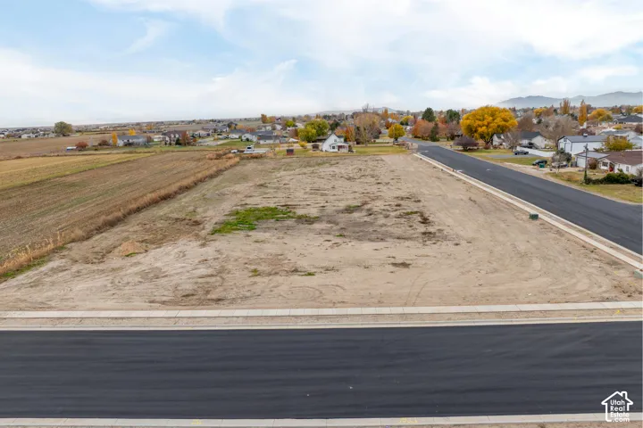 Expansive lot with newly paved street, concrete sidewalks, and surrounding residential area