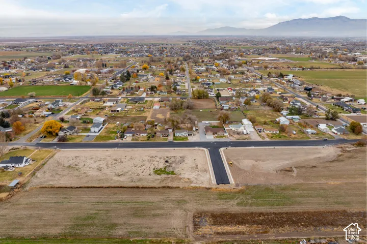 Expansive land parcel with graded terrain, established paved road infrastructure, and distant mountain scenery