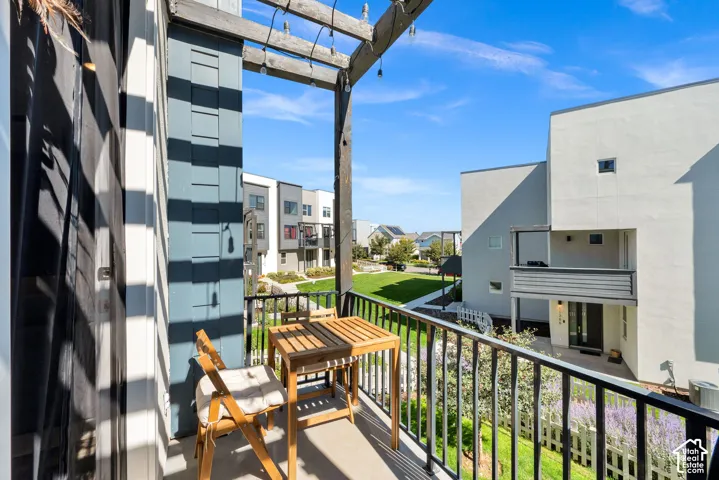 Private balcony with a concrete floor and a black metal railing, offering exterior views of a green space