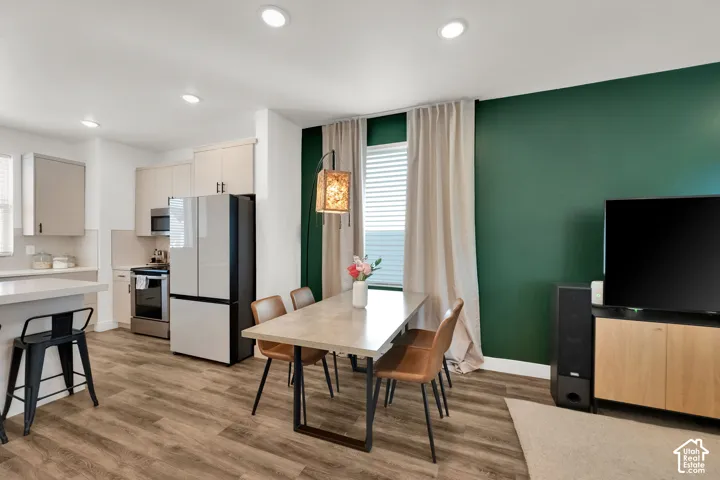 Open-concept kitchen and dining area featuring wood-finish flooring, recessed lighting, and a white quartz countertop