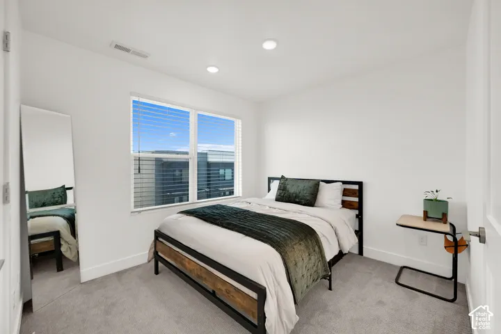 Recessed lighting with a white ceiling, light gray carpet, and a double window with blinds