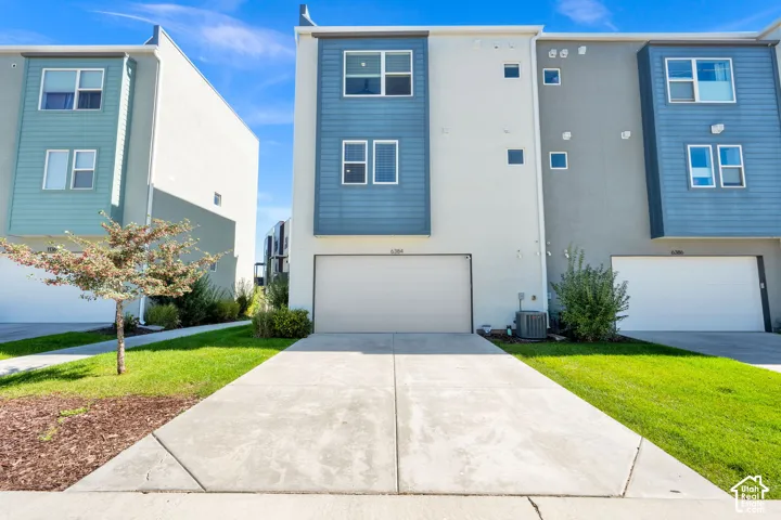Modern exterior featuring a prominent two-car garage, concrete driveway, and a combination of horizontal siding and stucco finishes