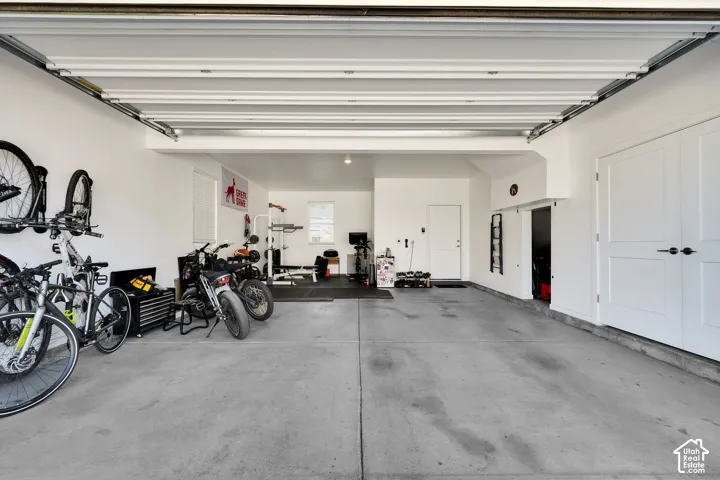 Spacious garage featuring a concrete floor, white walls, and a white interior door
