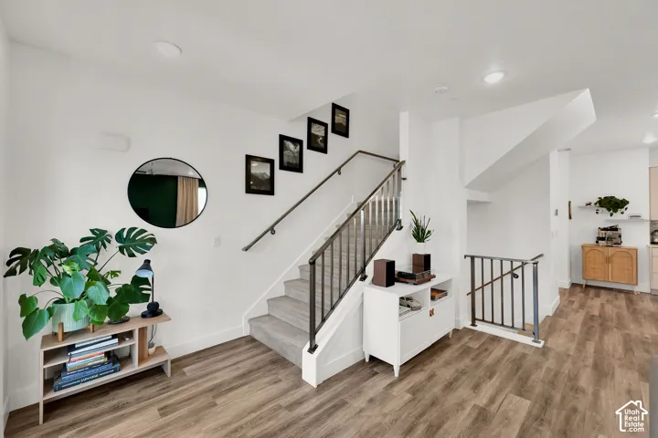 Wood-finish flooring, white walls, and a staircase with a metal railing