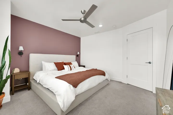 Ceiling fan with integrated lighting, recessed ceiling lighting, wall-mounted sconces, wood-finish nightstands, and a flush-panel door
