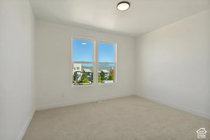 Bright and airy bedroom flooded with natural light through dual large windows framing expansive neighborhood vistas