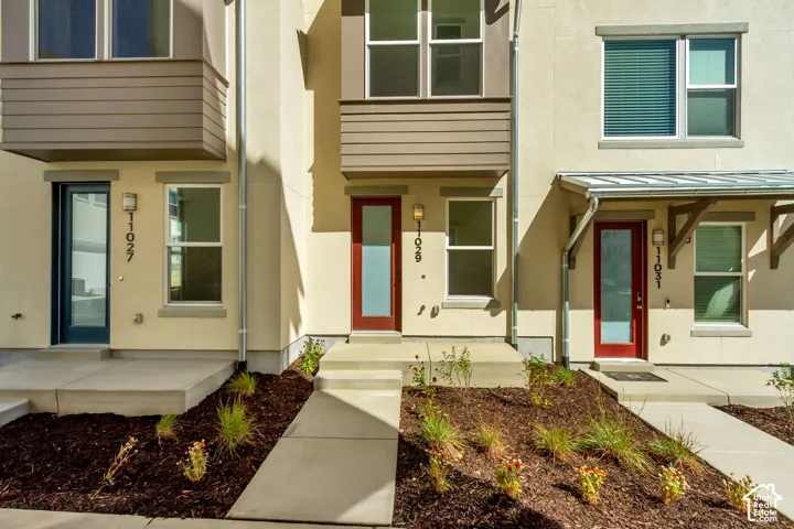 Contemporary exterior with stucco facade, contrasting horizontal siding, red-paneled entry doors, and a metal awning over the entryway