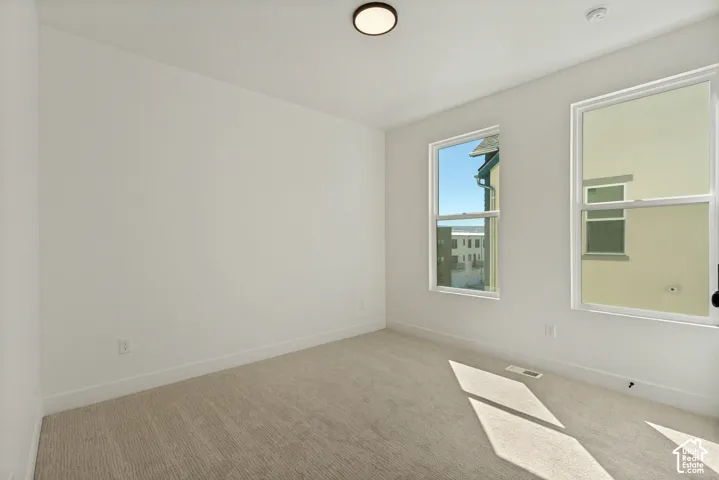 Neutral wall color, carpet flooring, recessed lighting, and two windows with white trim