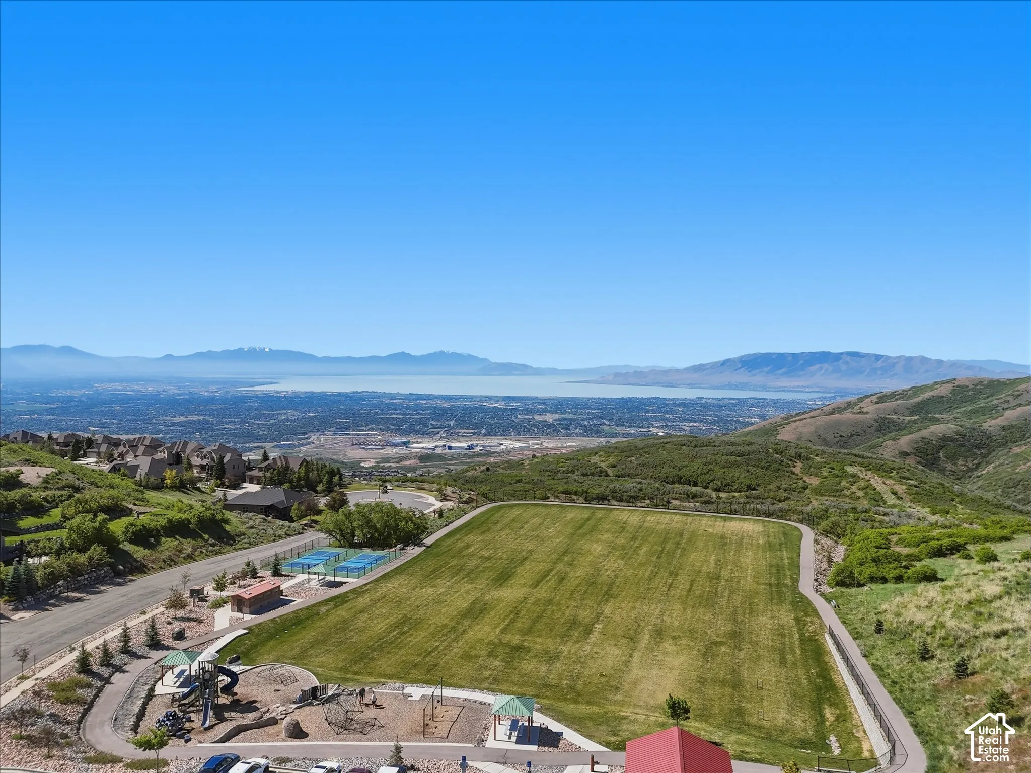Expansive green space with manicured lawn, playground, and tennis courts