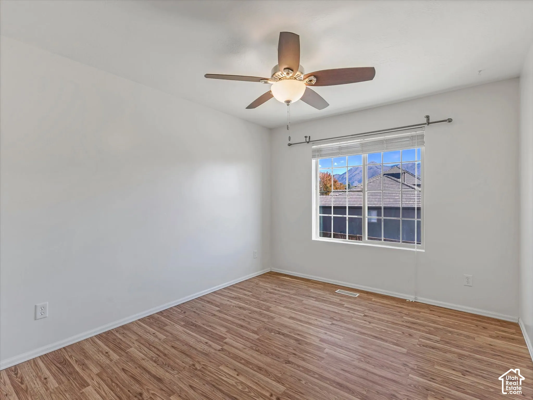 Wood-finish flooring, ceiling fan with integrated lighting, and a window with blinds