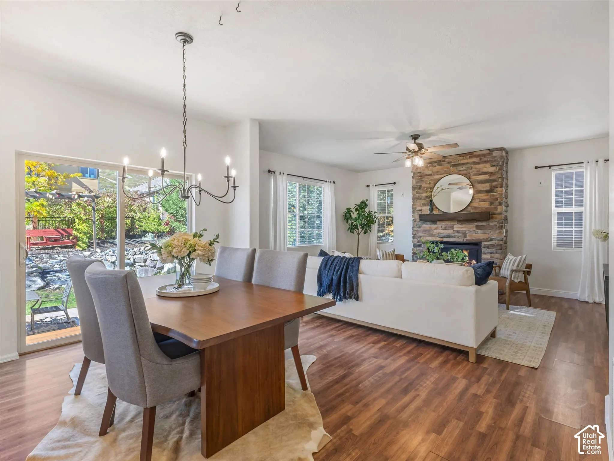 Wood-finish flooring throughout, a stone-clad fireplace with a wood mantel, and sliding glass doors