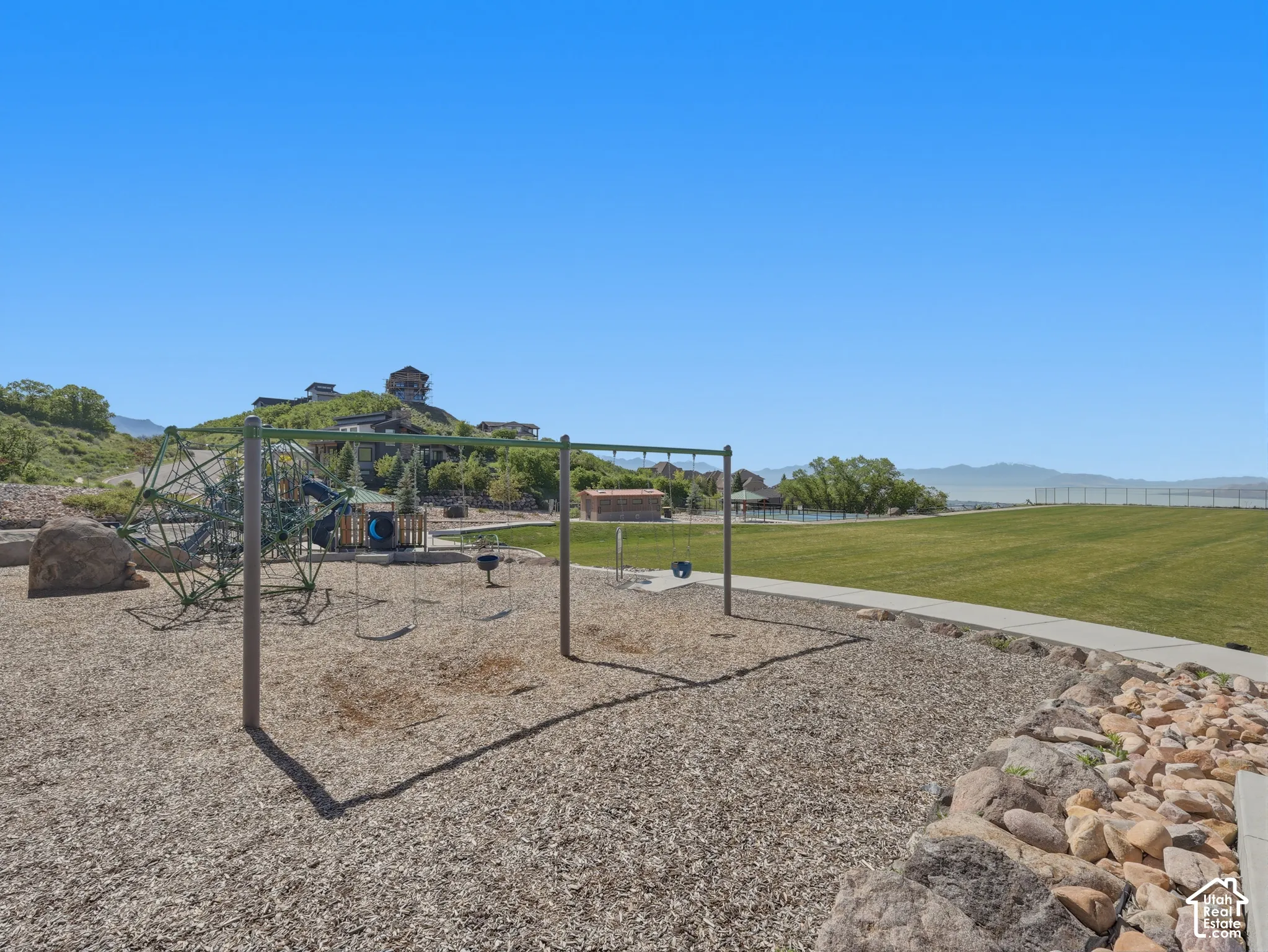 Playground area featuring swings, climbing structures, and a wood chip surface