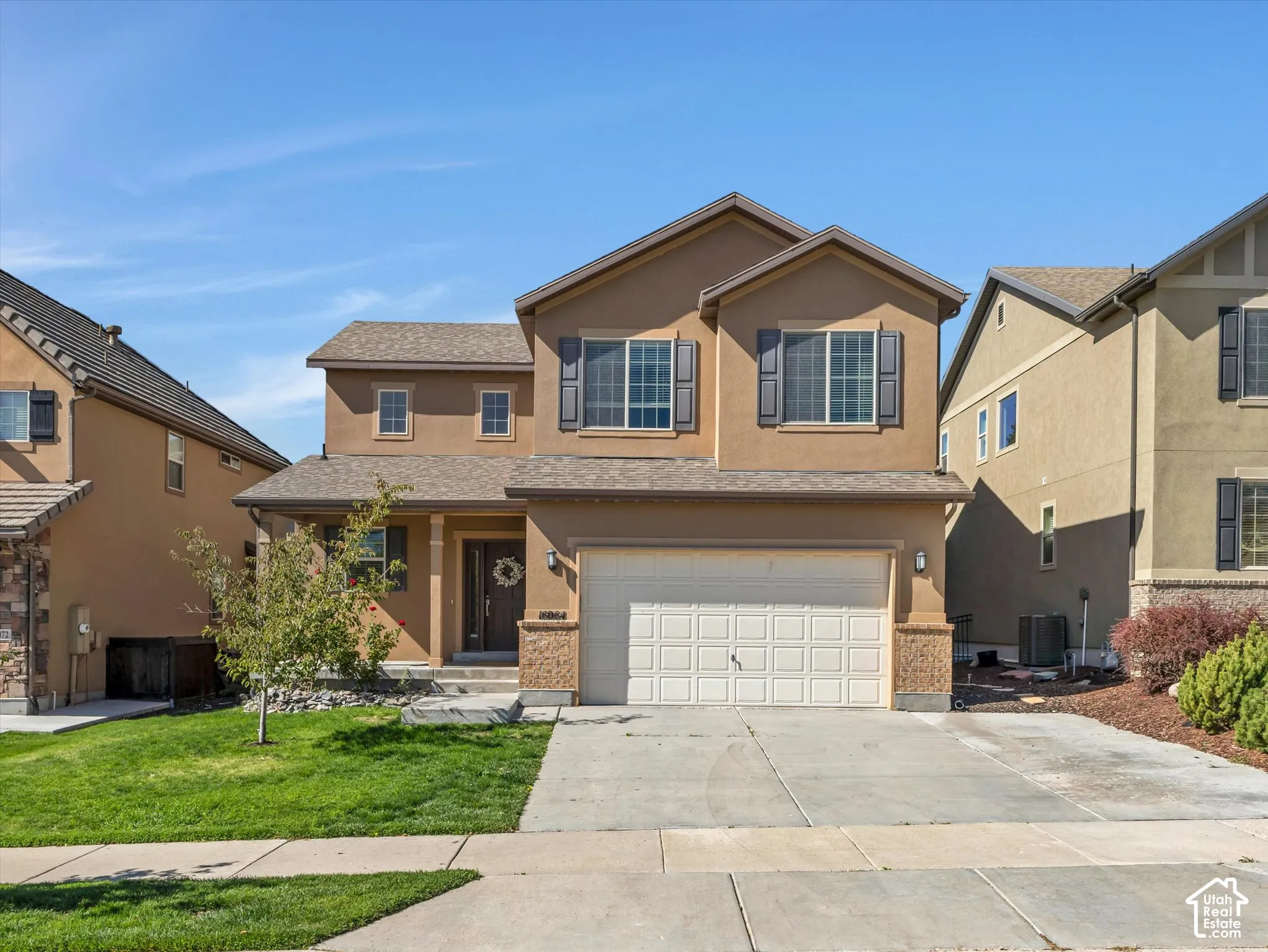 Two-story stucco exterior with decorative shutters, an attached two-car garage, and a covered front entry