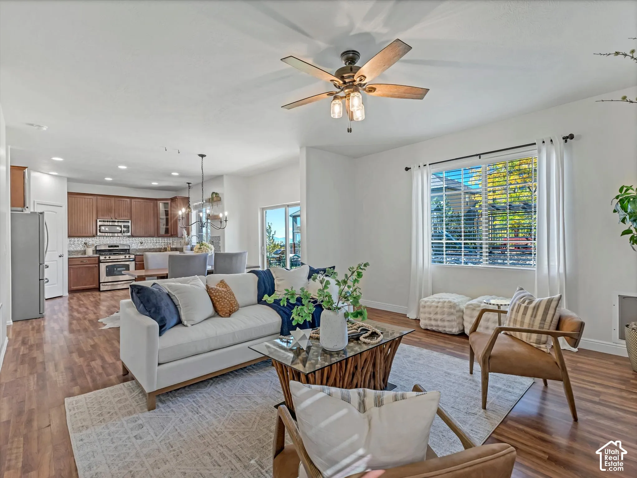 Open concept living area featuring wood-finish flooring, a ceiling fan with integrated lighting, and white window blinds