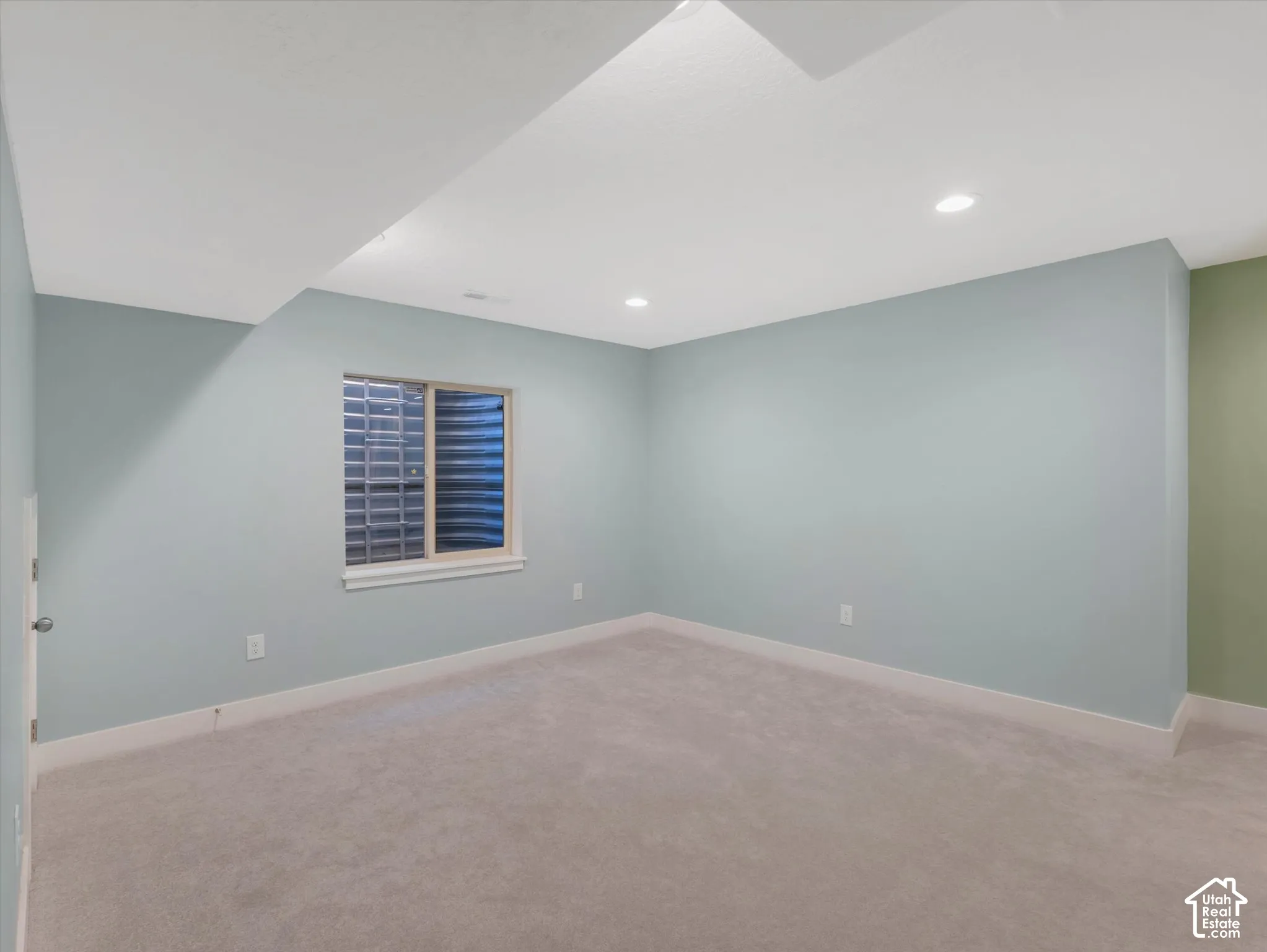 Recessed lighting, light-toned carpeting, window with privacy glass block, light blue and green wall finishes