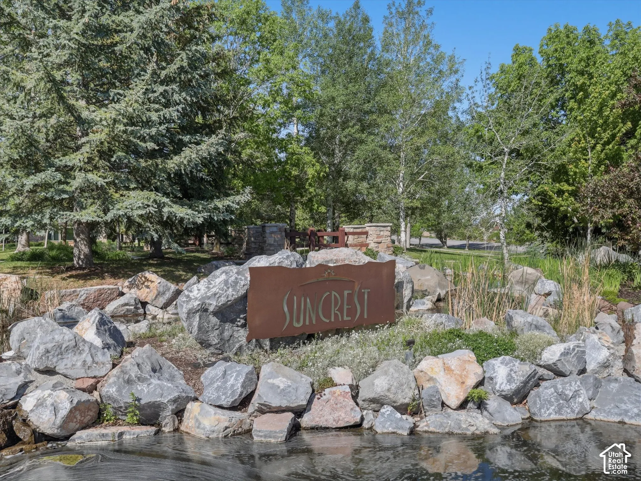 Stone and rock hardscaping with a water feature, accentuating the "SUNCREST" sign