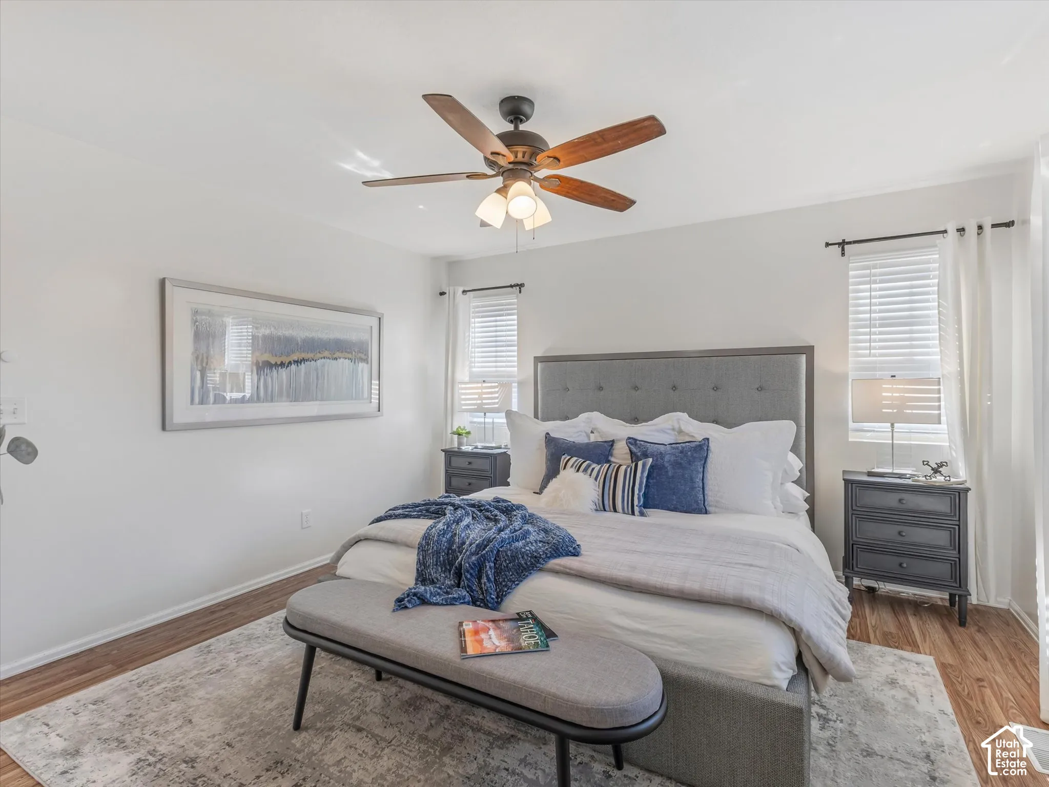 Wood-finish flooring with white walls and a ceiling fan