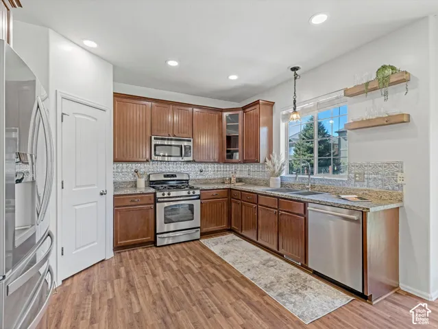 Kitchen featuring wood-finish flooring, granite countertops, stainless steel appliances, and wood cabinetry