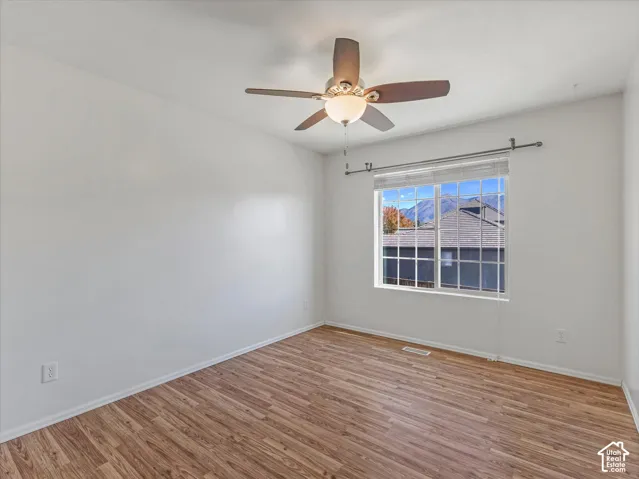 Wood-finish flooring, ceiling fan with integrated lighting, and a window with blinds