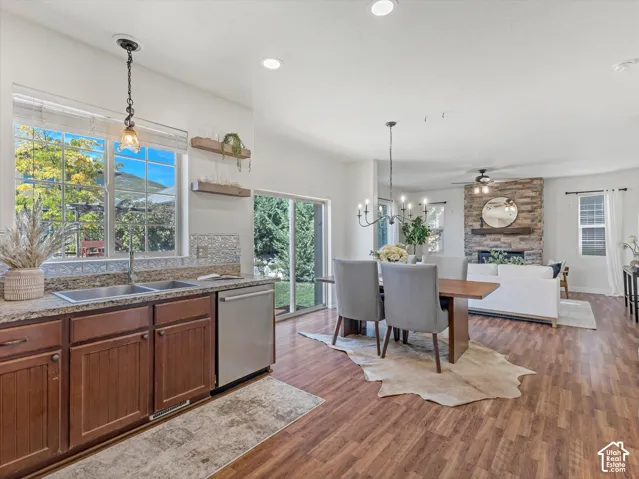 Kitchen featuring granite countertops, a double stainless steel sink, wood-finish flooring, and a sliding glass door to the exterior
