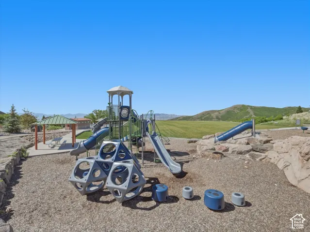 Community playground featuring multiple slides, climbing structures, and a shaded picnic area