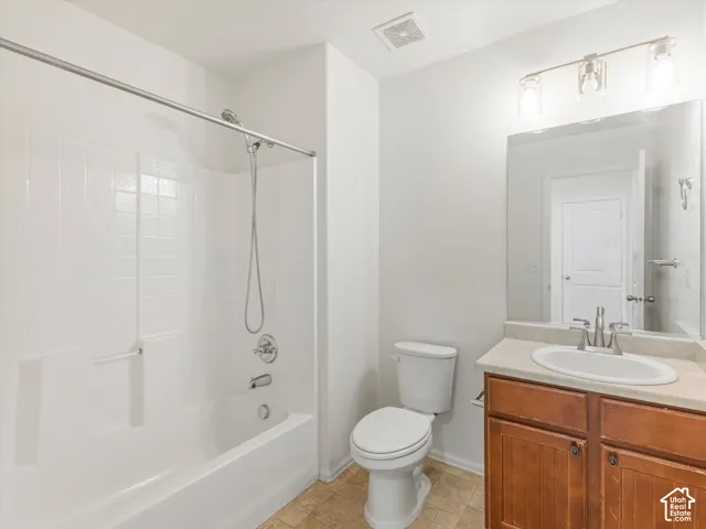 Tub and shower combination with white tile surround, vanity with wood-finish cabinetry, integrated sink, and large wall-mounted mirror