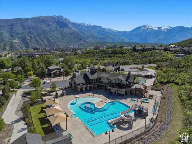 Expansive community pool with multiple swimming areas, integrated water slide, and adjacent spa