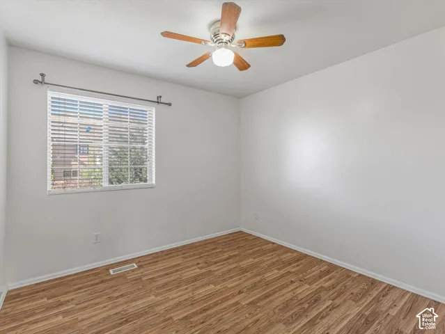 Hard-surface wood-finish flooring, white walls, and a ceiling fan with integrated lighting