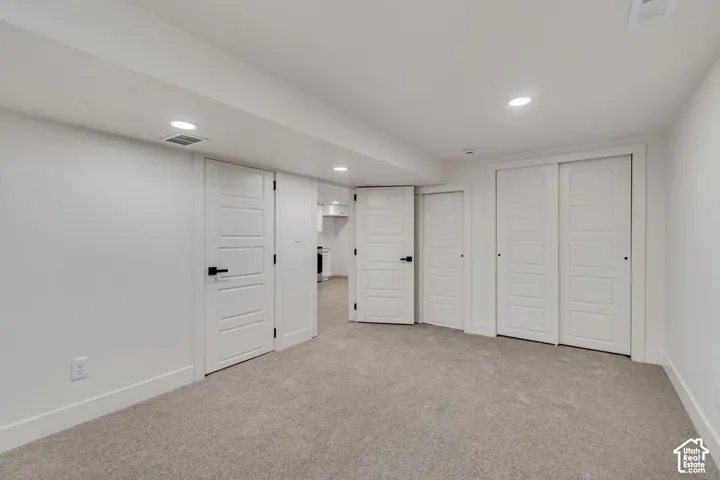 Plush carpeting, recessed lighting, and multiple panel doors with matte black hardware