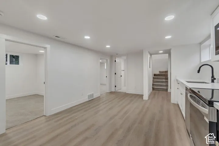 Open-concept basement featuring wood-finish flooring throughout, recessed ceiling lighting, and white drywall construction