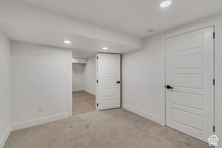 Recessed lighting, wood-finish flooring, two panel doors with matte black hardware, and gray carpeting