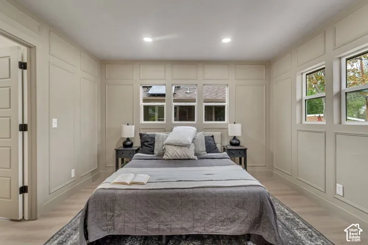 Wall paneling details, recessed lighting, multiple windows, light wood-finish flooring, and a solid core door