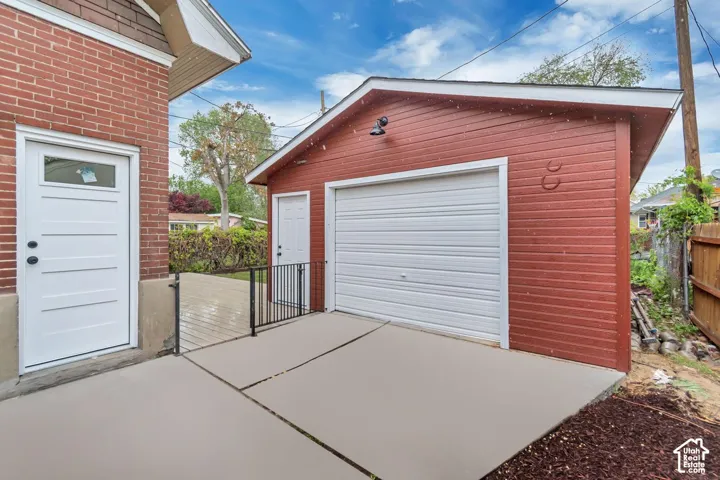 Brick exterior with a white entry door, an exterior light fixture, and a concrete patio