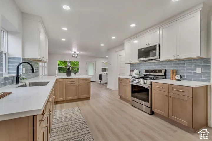 Chef's kitchen featuring white cabinetry, wood-finish lower cabinets, stainless steel appliances, subway tile backsplash, quartz countertops, recessed lighting, and a large center island with prep space
