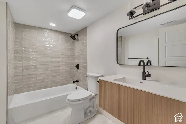 Modern bathroom featuring a built-in tub with textured wall tile, sleek vanity with integrated sink, and matte black fixtures