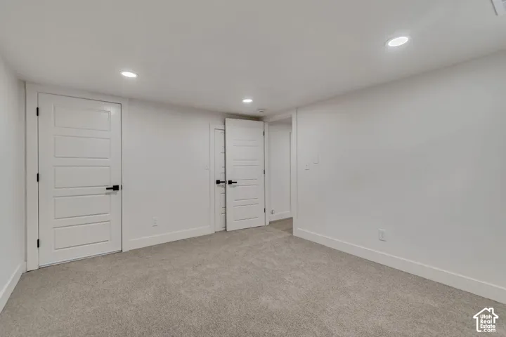 Recessed lighting illuminates the neutral carpet and white walls